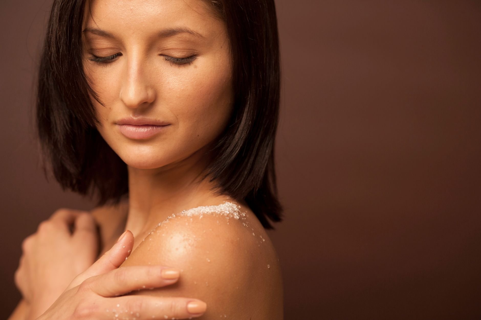 Close-up of a woman enjoying a luxurious skincare routine in a warm studio setting